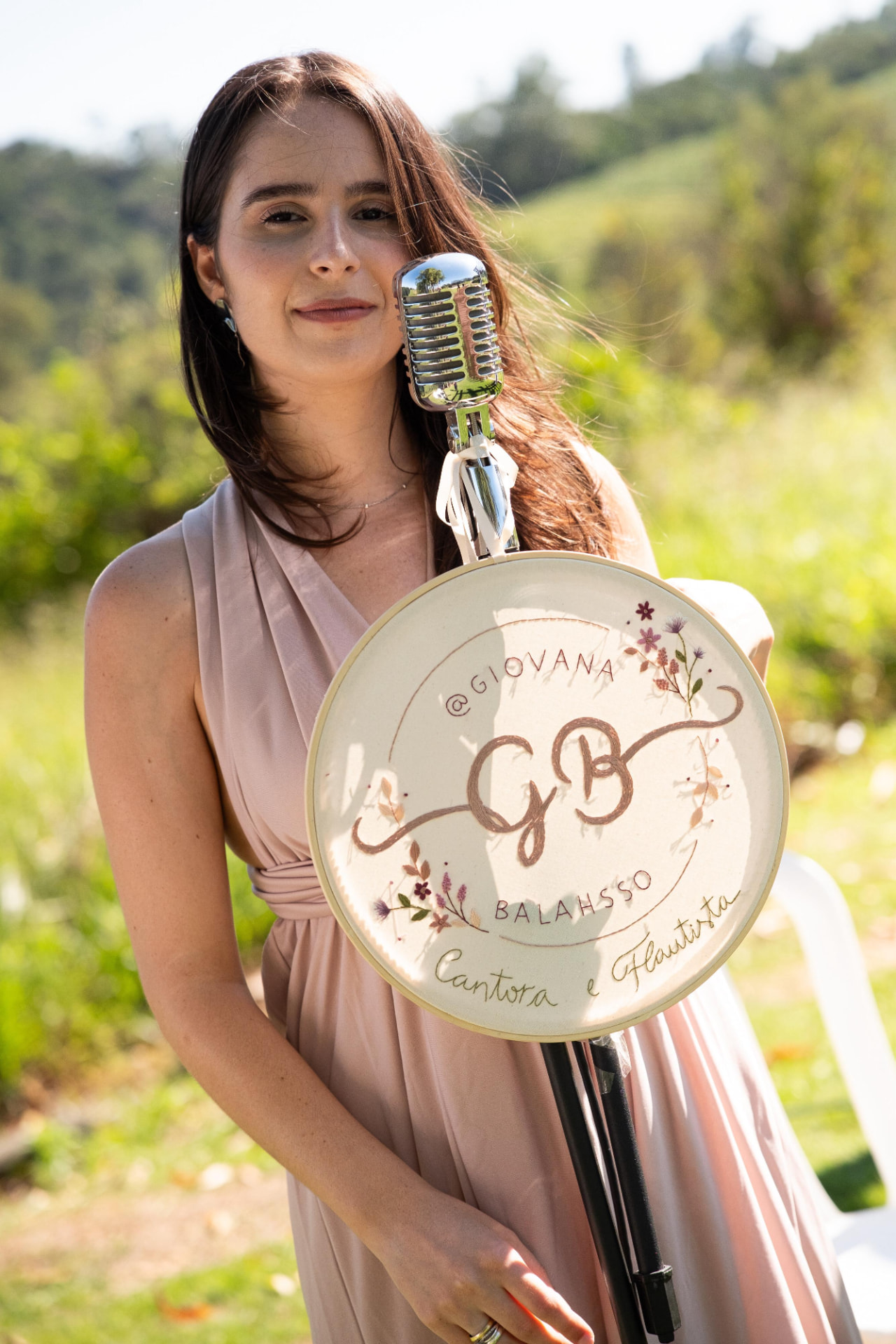 Giovana ao sol com microfone e bastidor bordado